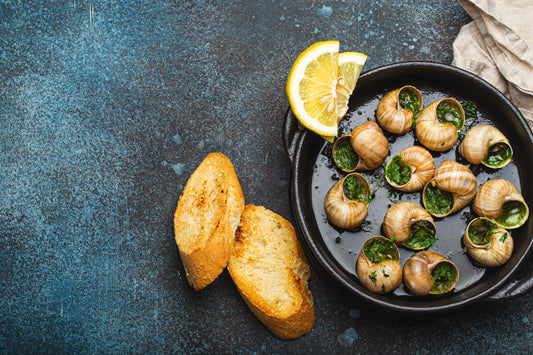 Escargots à la Bourguignonne serviți cu lămâie și pâine prăjită